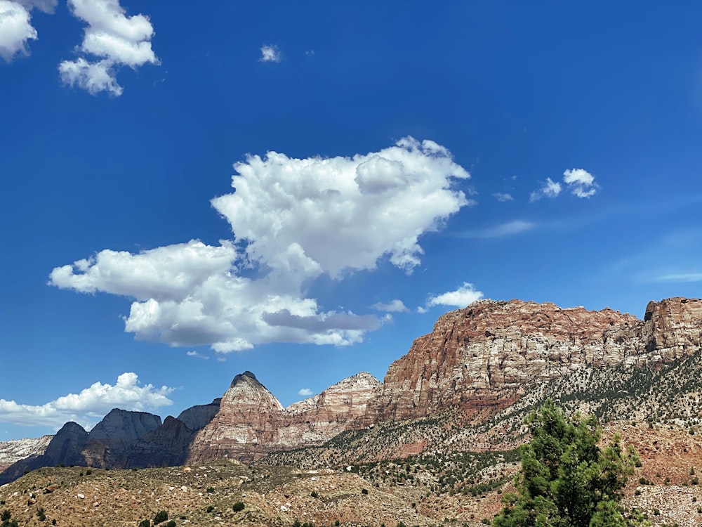 昼間の青空と白い雲の下の茶色の岩山