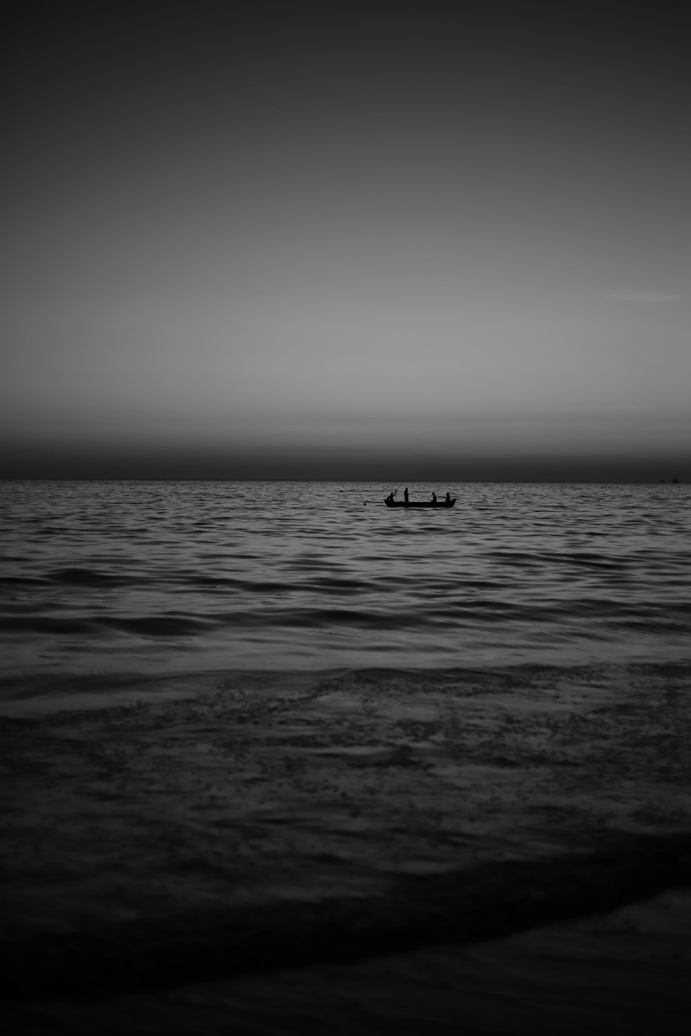 grayscale photo of person riding on boat on sea