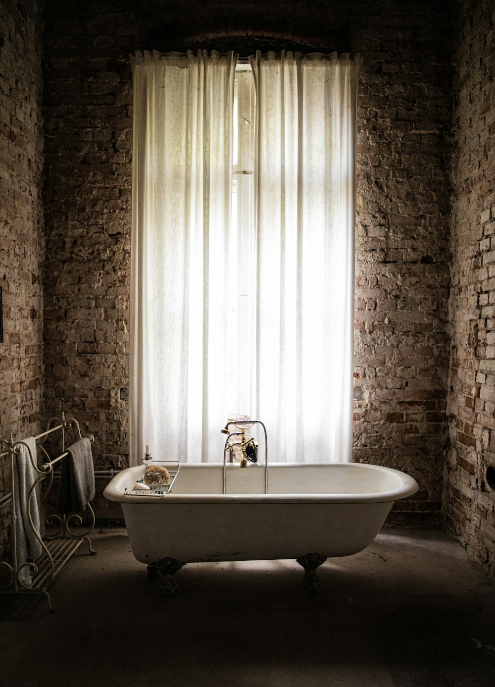 white ceramic bathtub near white window curtain