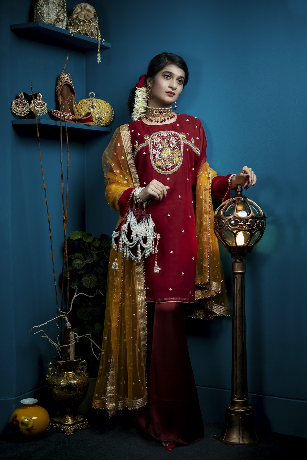 woman in red and gold sari standing beside green wall