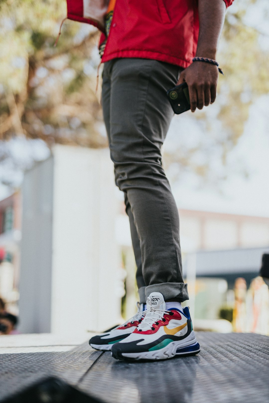 person in black denim jeans and black white and red nike sneakers