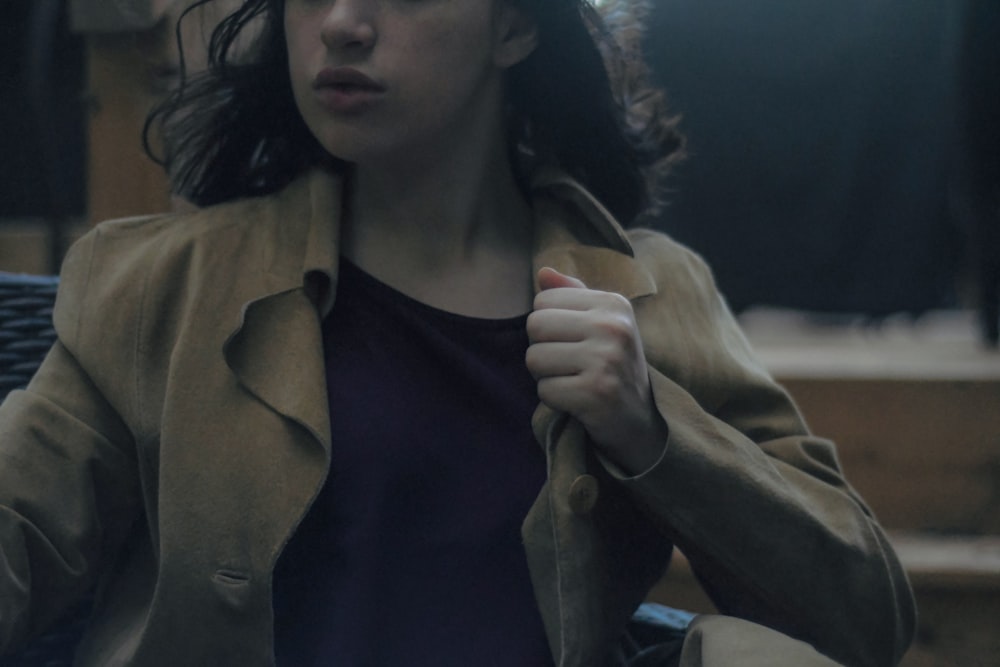 woman in brown coat holding cigarette stick