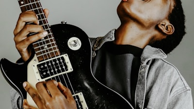 man in black leather jacket playing electric guitar