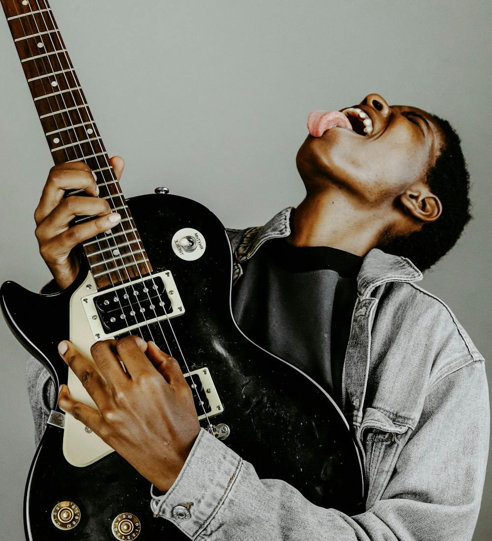 man in black leather jacket playing electric guitar