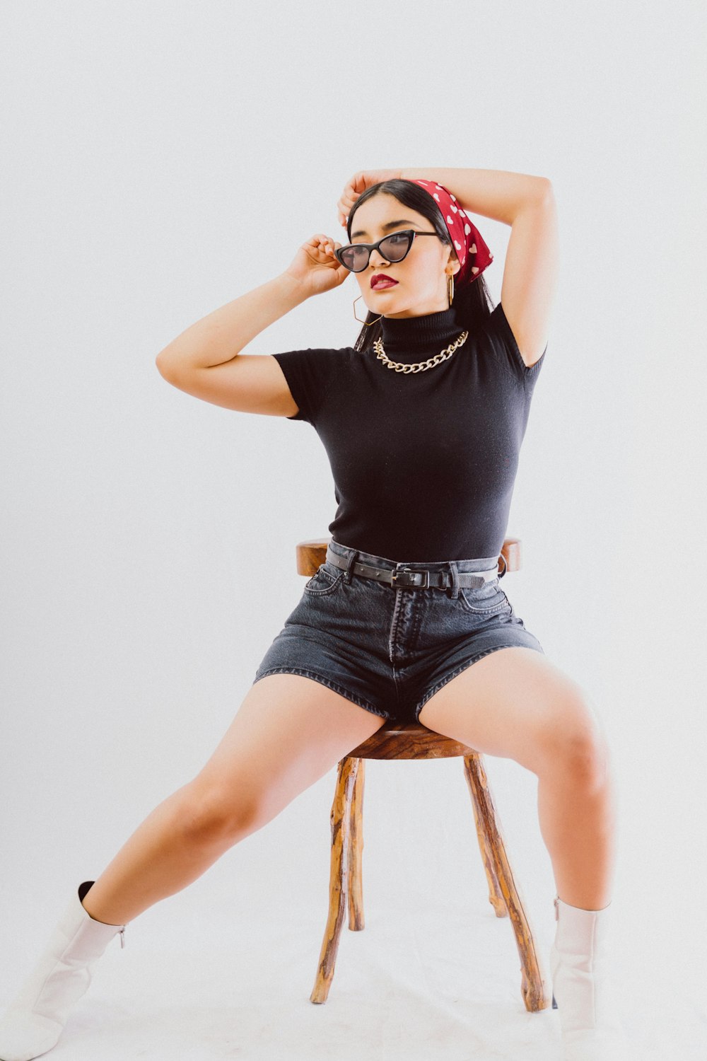 woman in black tank top and blue denim shorts sitting on brown wooden seat