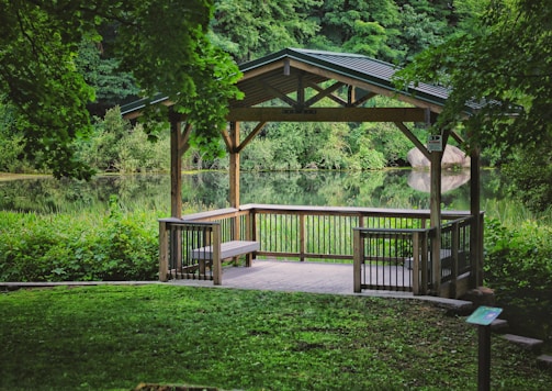 brown wooden gazebo near green trees during daytime