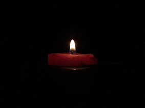 red lighted candle on dark room