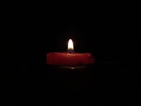 red lighted candle on dark room