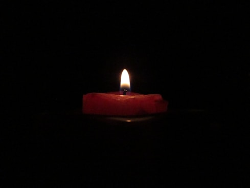 red lighted candle on dark room