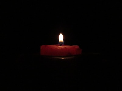 red lighted candle on dark room
