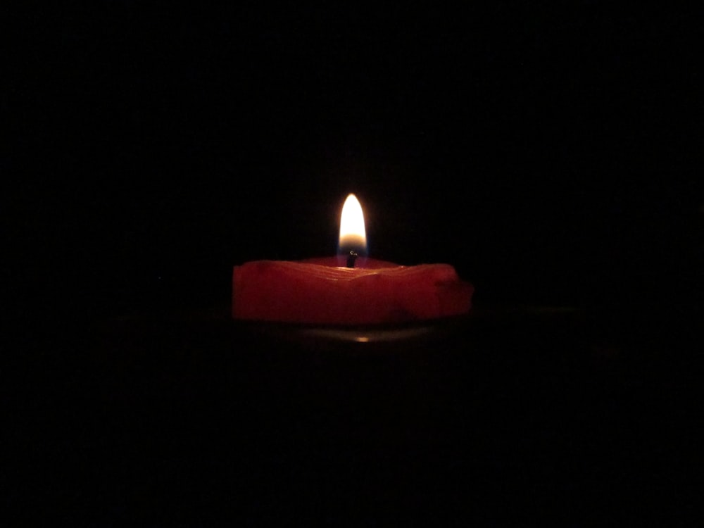 red lighted candle on dark room