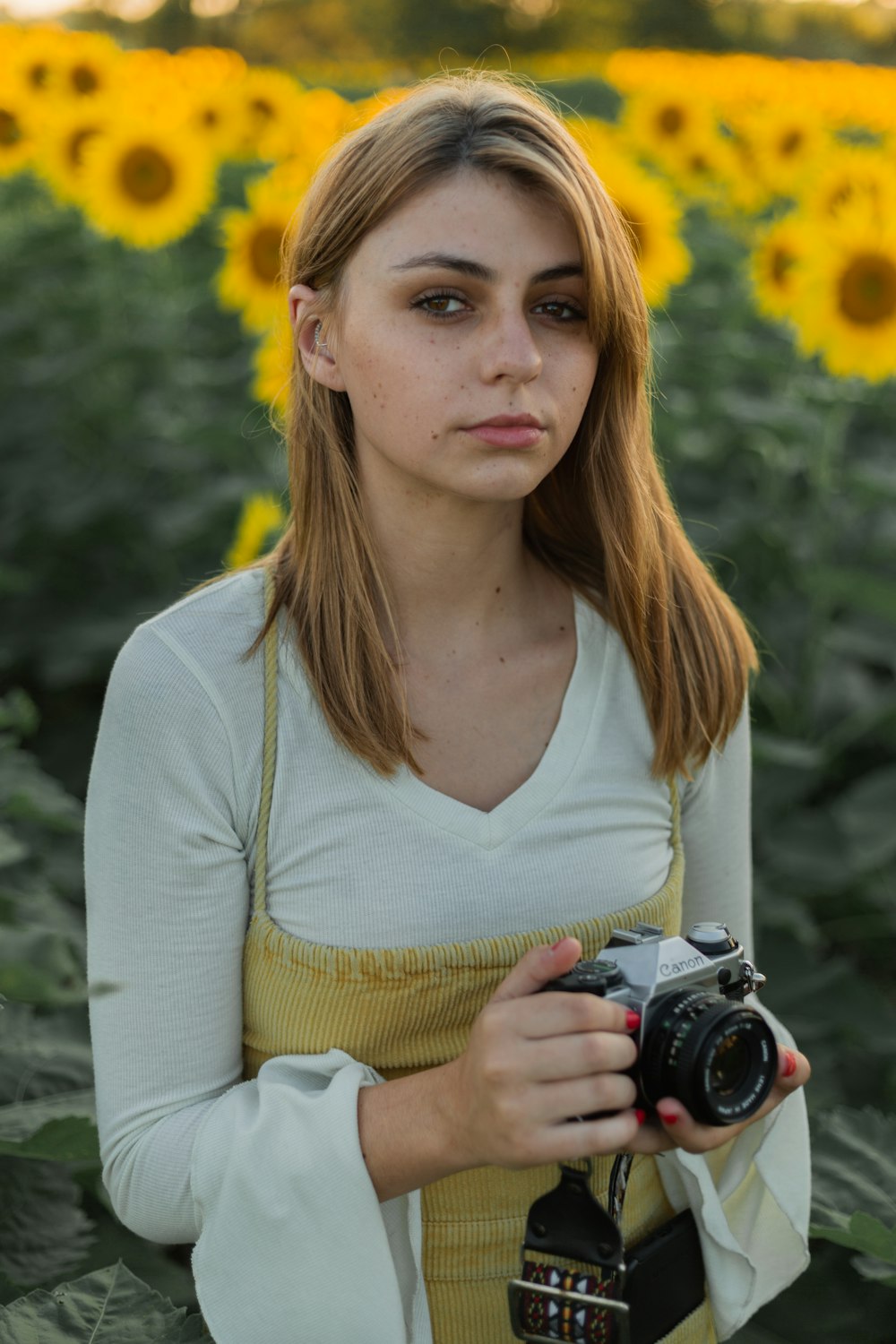 woman in yellow cardigan holding black camera