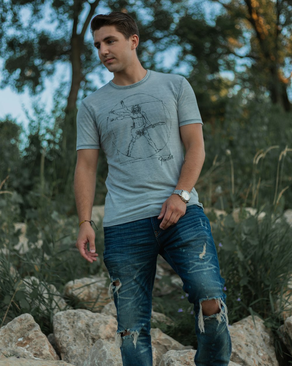 man in gray crew neck t-shirt and blue denim jeans standing on gray rock during