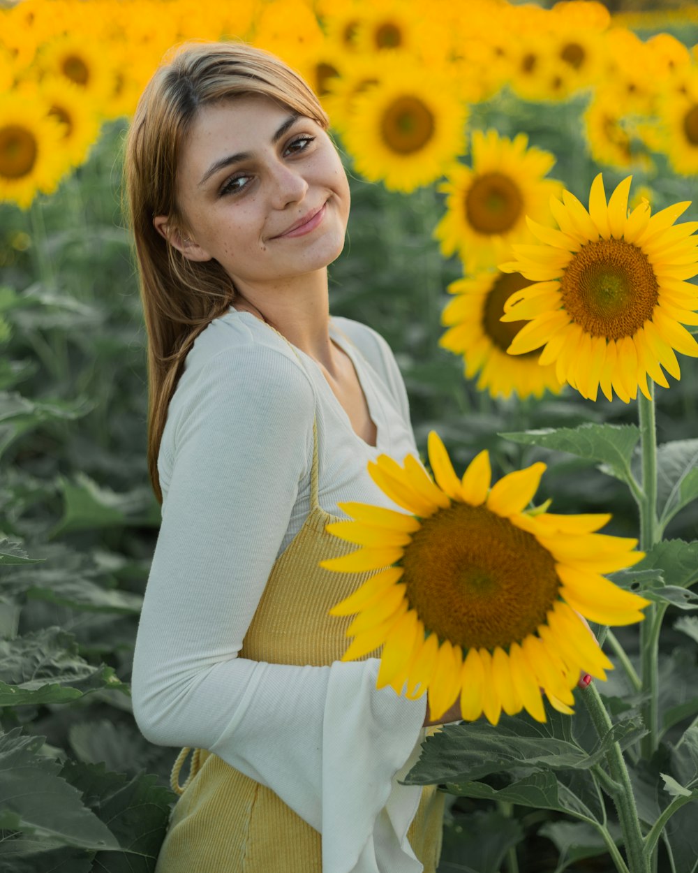woman in white long sleeve shirt holding sunflower
