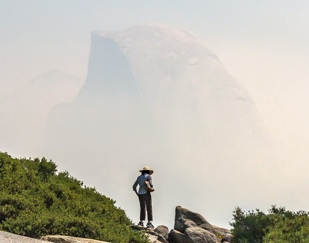 man in black t-shirt and black shorts standing on rock formation during daytime