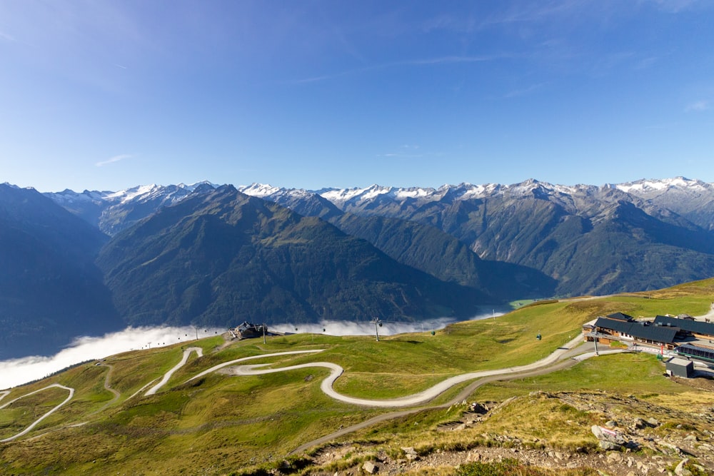 campo di erba verde vicino alla montagna sotto il cielo blu durante il giorno