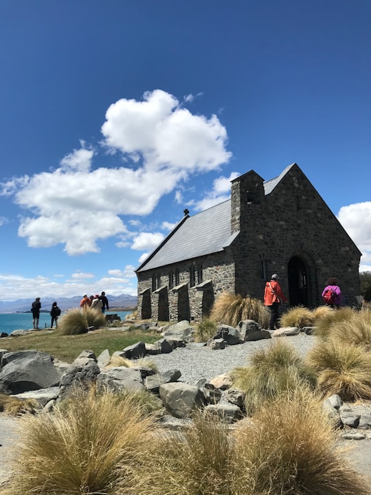 people walking near black and gray concrete building under blue sky during daytime in Church of the Good Shepherd New Zealand