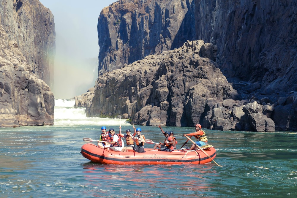 people riding on red kayak on water during daytime