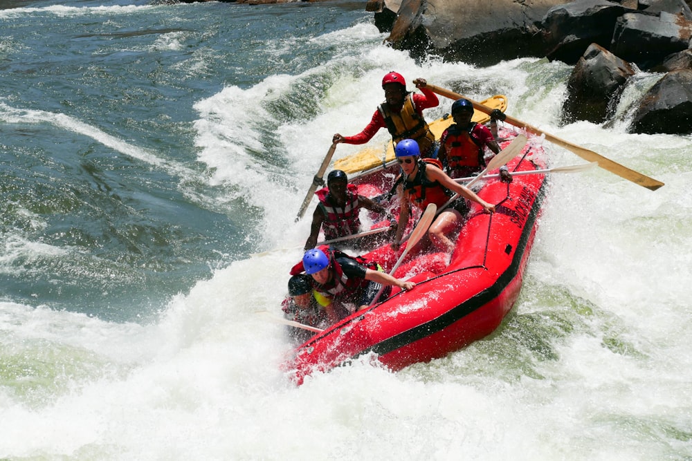 2 men riding red kayak on sea during daytime