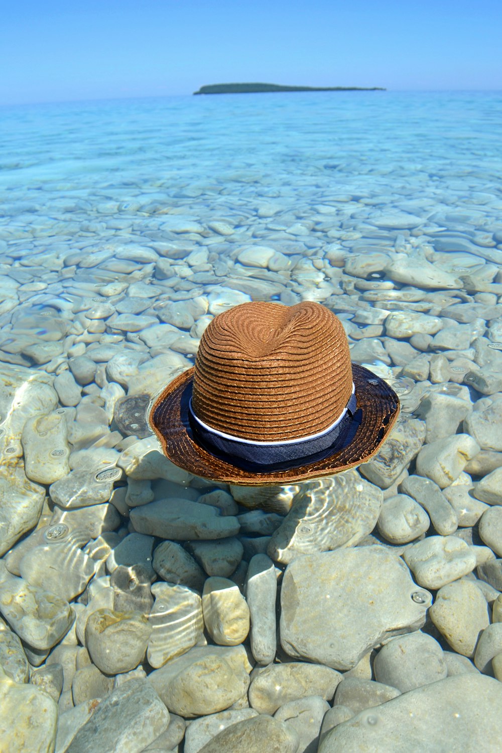 brown and black fedora hat on gray stone