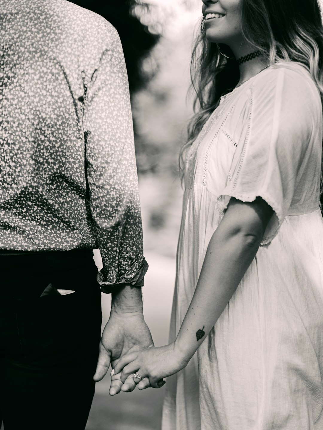 grayscale photo of man and woman holding hands