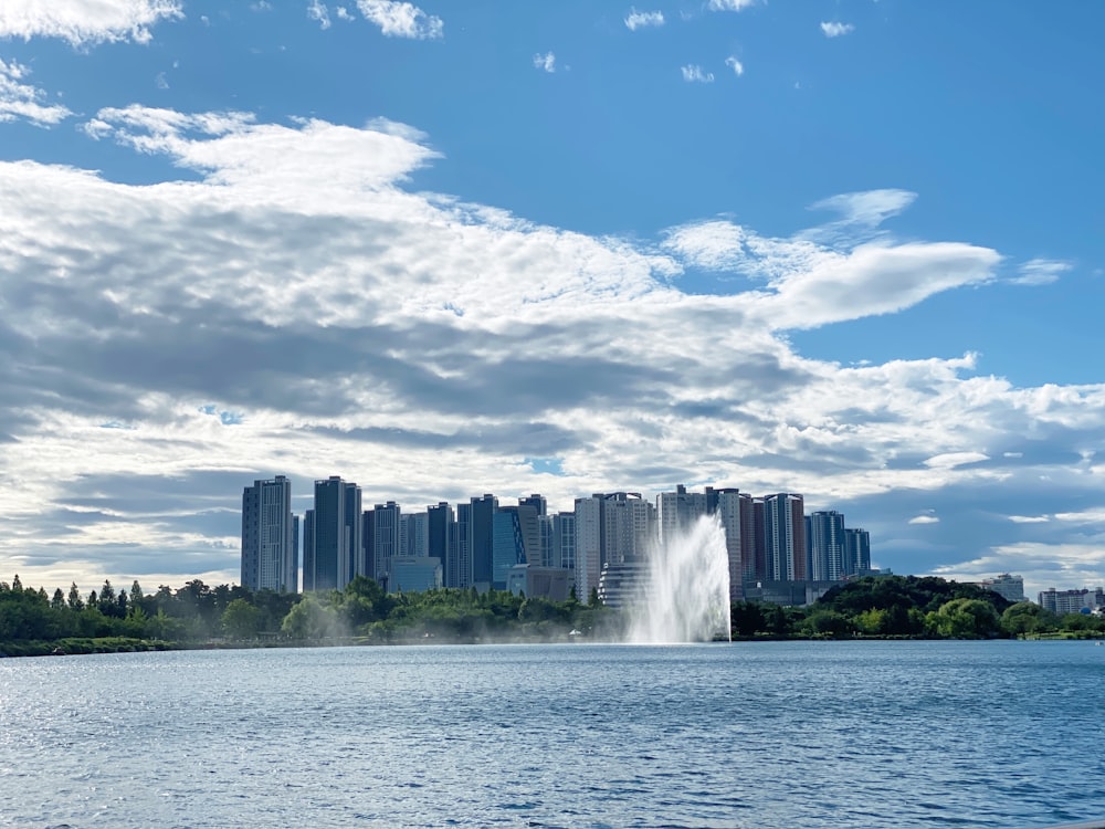 Wasserfontäne in der Nähe von Stadtgebäuden unter blau-weißem sonnigem Wolkenhimmel tagsüber