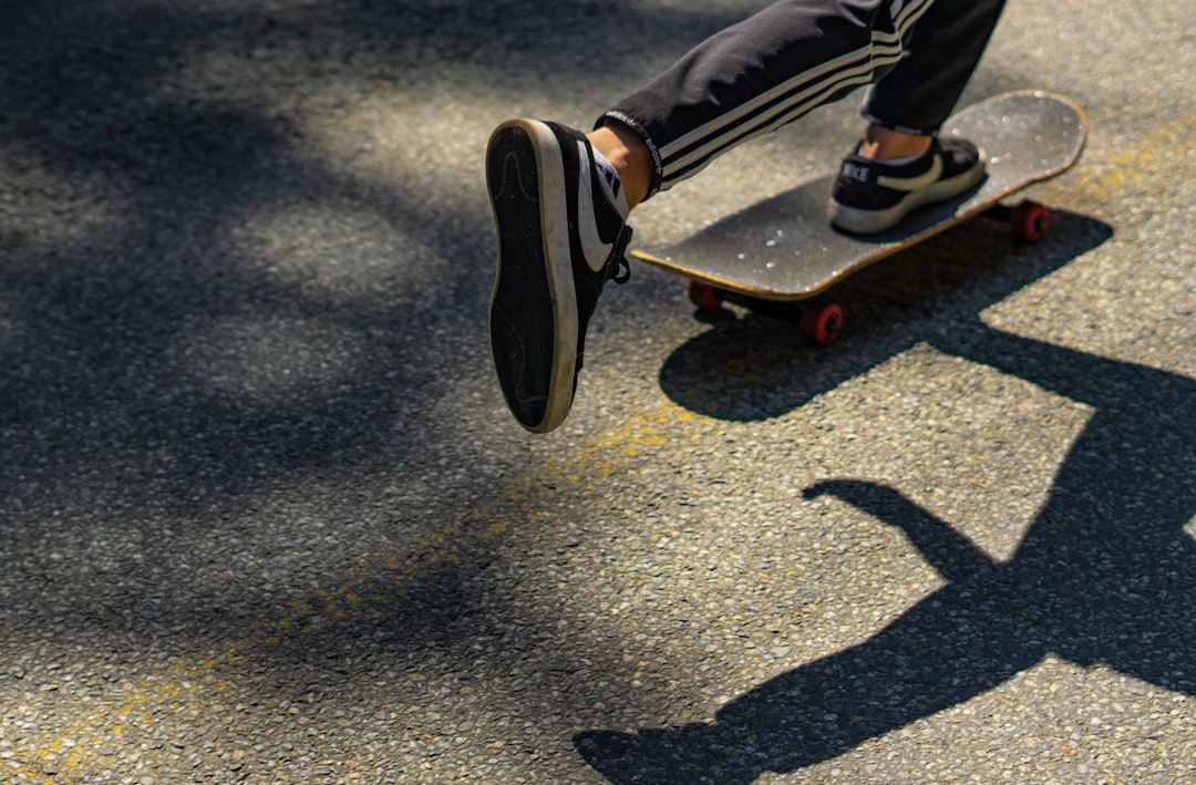 person in black and red sneakers riding skateboard