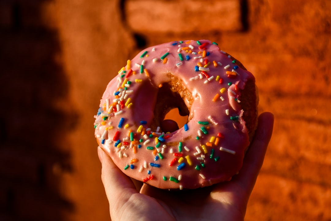 person holding doughnut with sprinkles