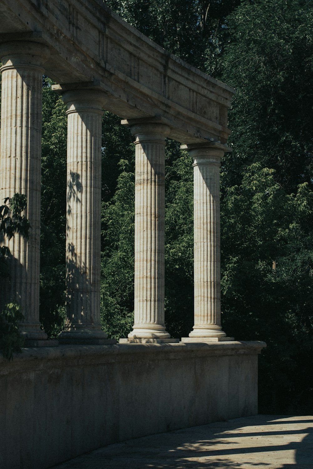 white concrete pillar near green trees during daytime