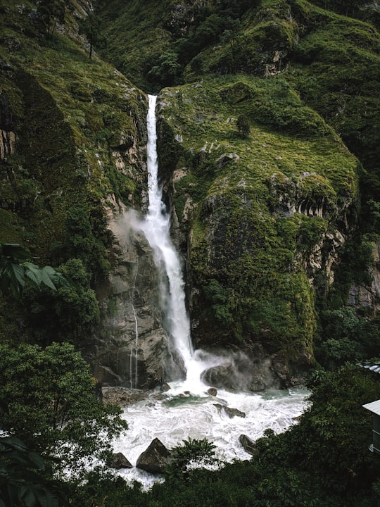 waterfalls in the middle of green trees in Annapurna Conservation Area Nepal