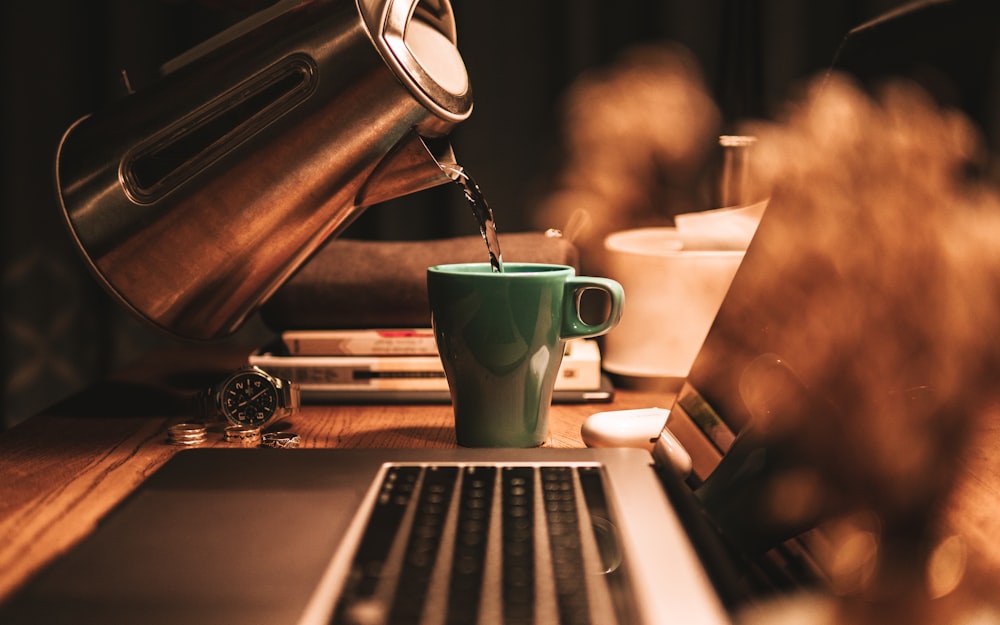 green ceramic mug on macbook pro