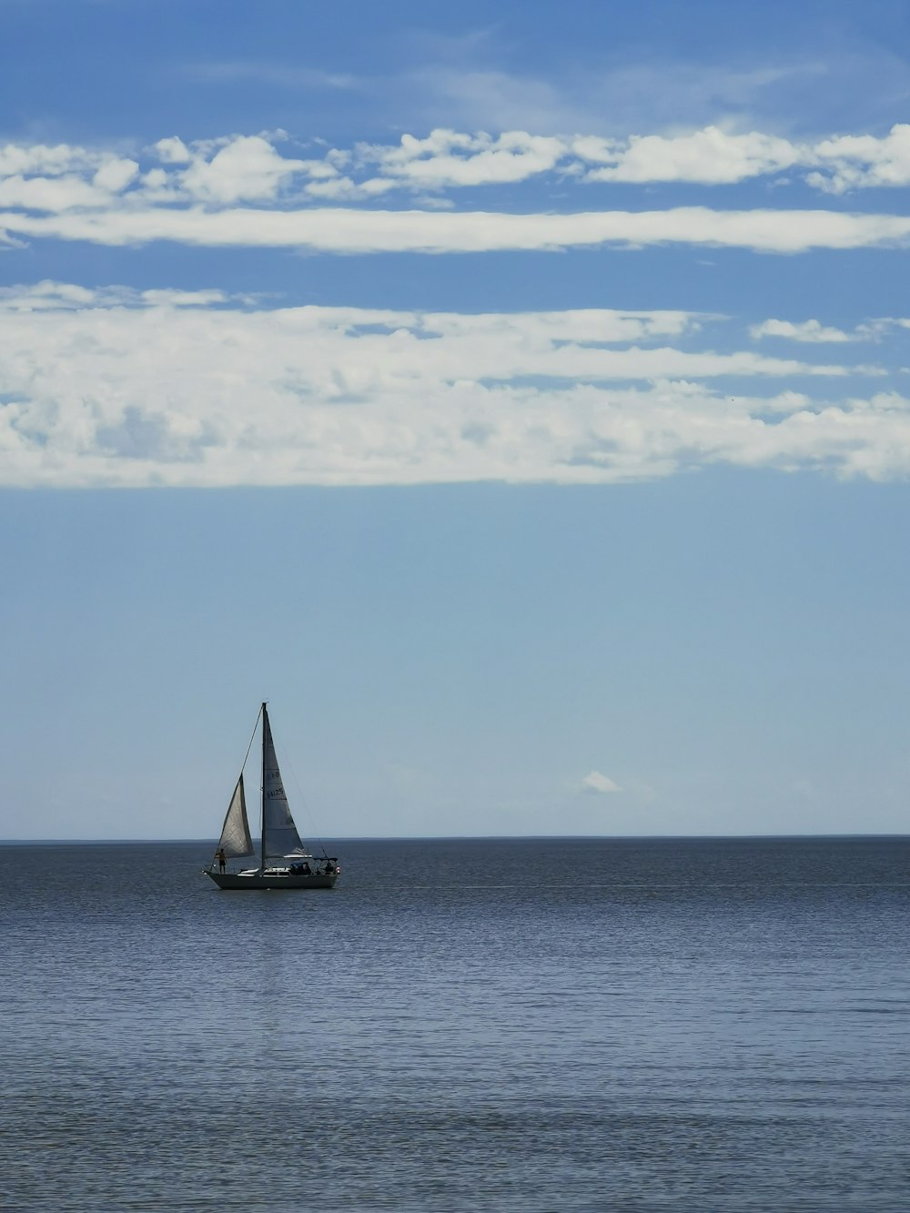 sailboat on sea under white clouds and blue sky during daytime