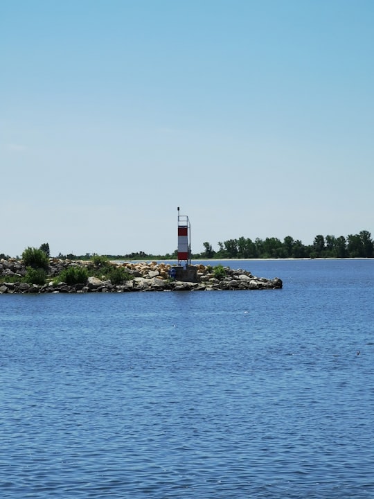 white and red lighthouse near body of water during daytime in Gimli Canada