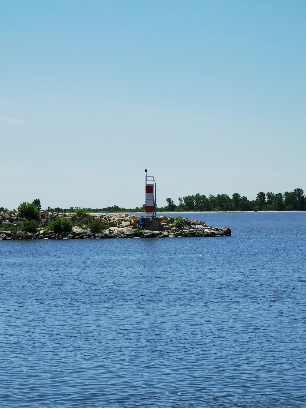 white and red lighthouse near body of water during daytime