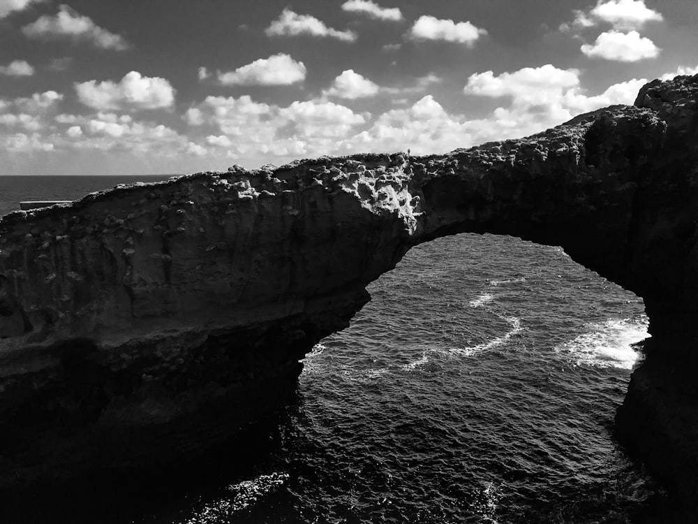 grayscale photo of rocky mountain near body of water