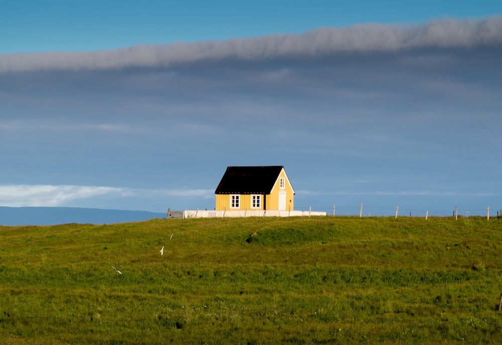 white and black house on green grass field under white clouds and blue sky during daytime