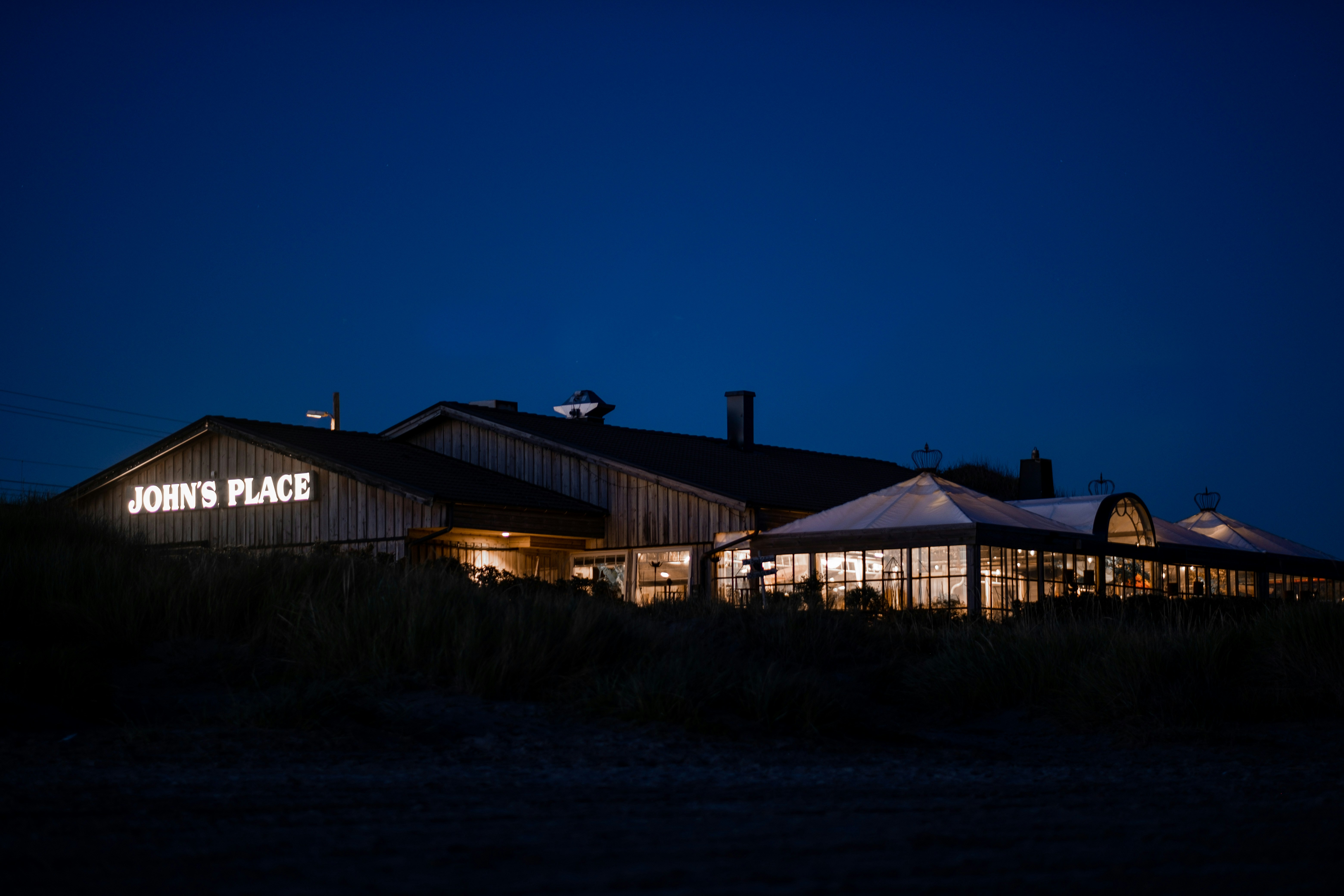 white and brown wooden house near green trees during night time