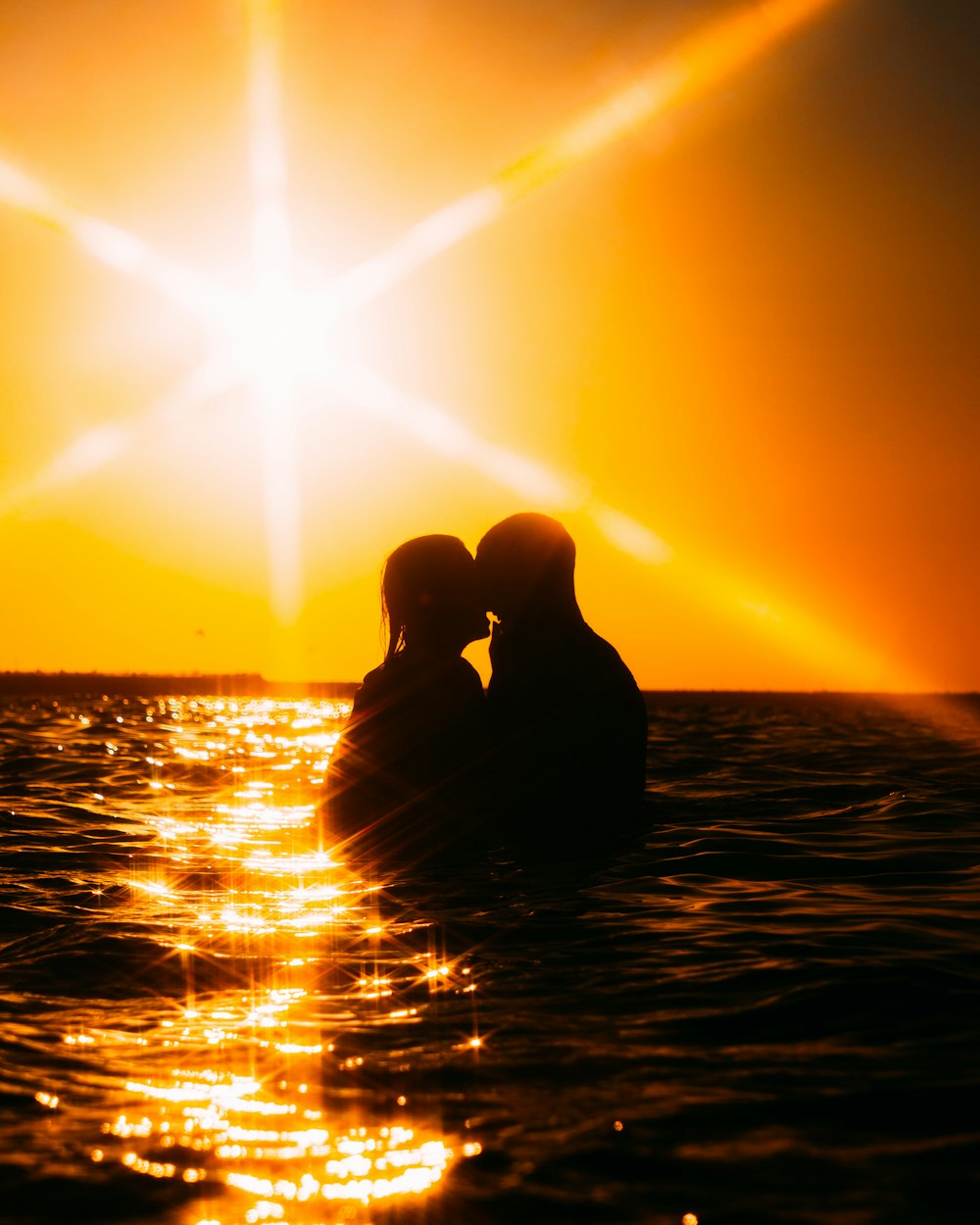 silhouette of couple kissing on sea during sunset