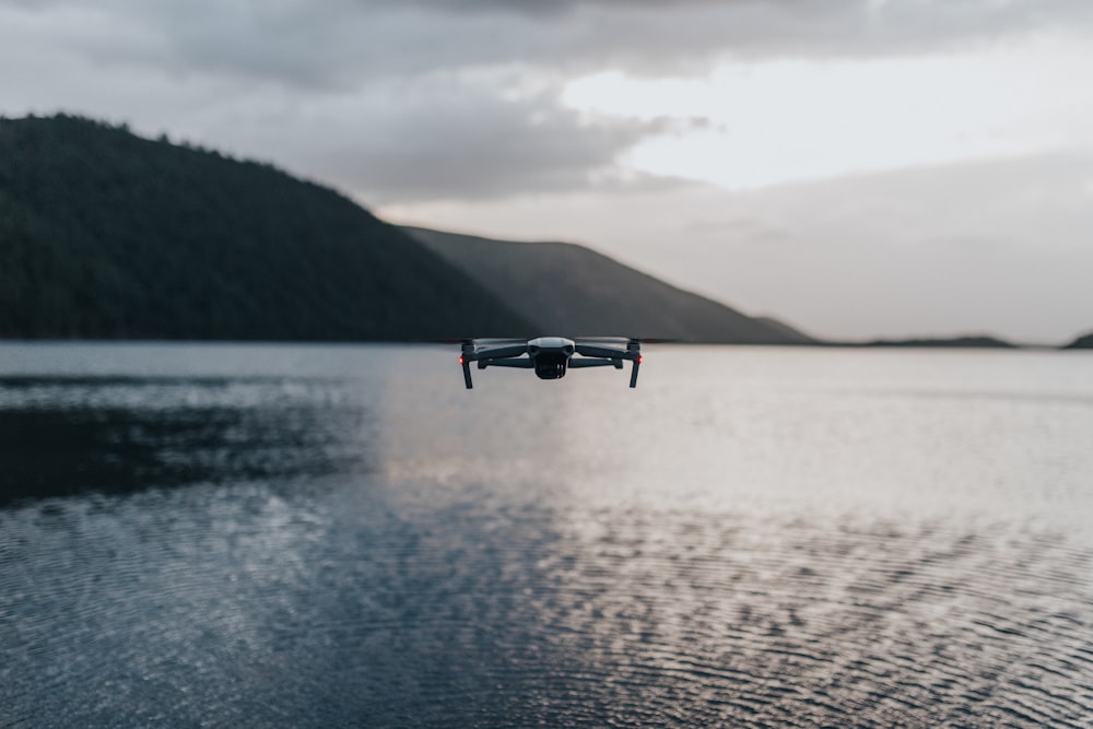 drone preto voando sobre o mar durante o dia