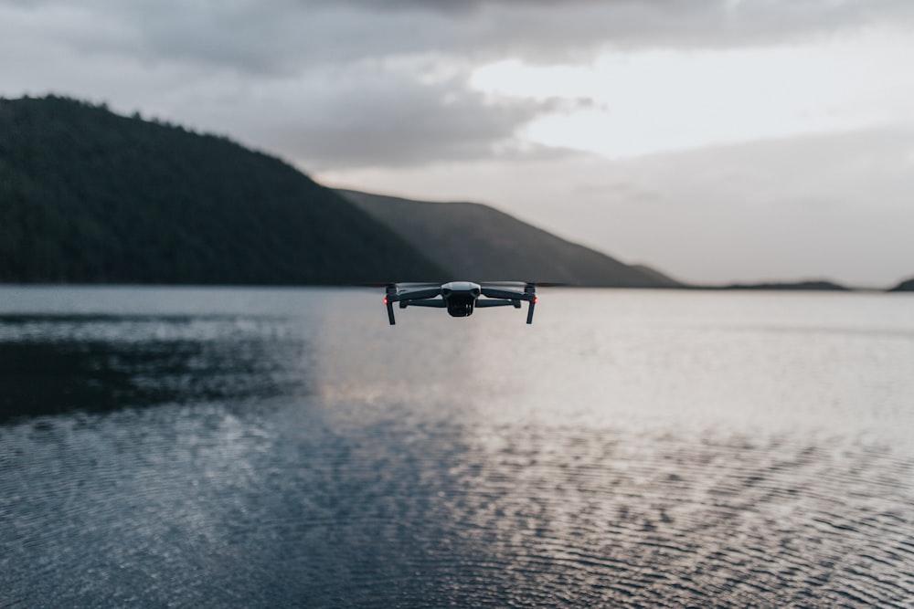 black drone flying over the sea during daytime