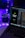 A laptop displaying code in an IDE is next to a mobile phone with an app featuring a green flame icon and the text 'Welcome to Pyro.' A white mug on the desk is illuminated by blue and purple ambient lighting. Potted plant leaves and a colorful LED strip add to the aesthetic setup.