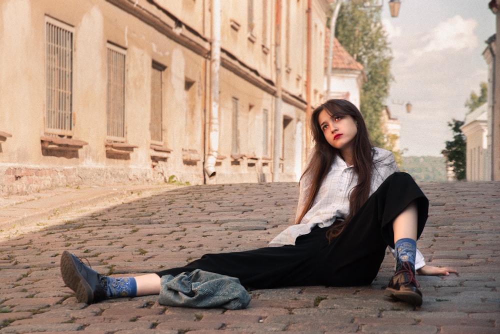 woman in white tank top and black pants sitting on brown concrete floor during daytime