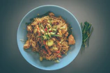 Elegant plating of stir-fried noodles with colorful vegetables and tender chicken.