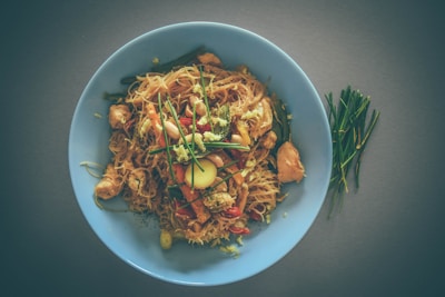 A steaming plate of silky noodles tossed with crunchy peanuts and vibrant herbs.