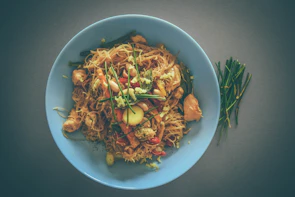 Elegant plating of stir-fried noodles with colorful vegetables and tender chicken.