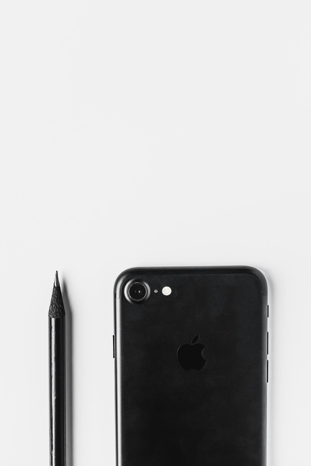 Schwarzes iPhone 7 Plus neben schwarzem Stift