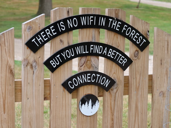 Sign on a wooden fence stating no WiFi connection (Photo by Ann / Unsplash)