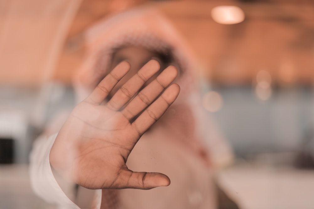 person in white long sleeve shirt covering face with hand