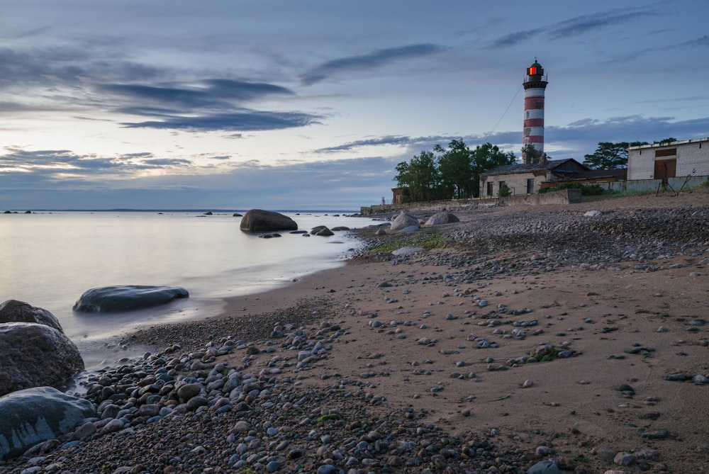 white and black lighthouse on seashore during daytime