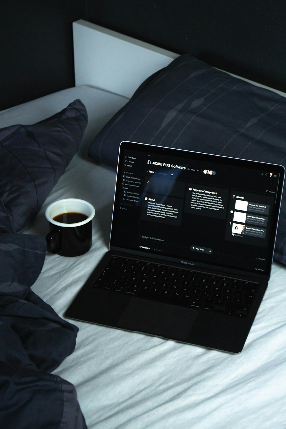 black laptop computer on white bed